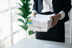 Businessman holding a lot of documents, corporate financial documents.